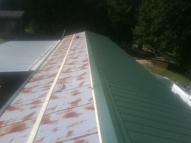 Old rusted panels beside newly installed green metal roofing — Wind Damage Roof Repair by Roofing Brothers in Derwood