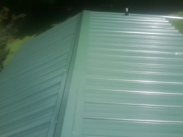 New green metal panels meeting at the ridge of a roof — Flat Roof Repair work by our crew in Derwood