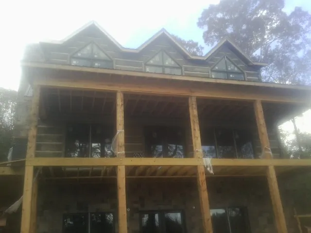 Dormers and porch framing on a large log home under construction — Roof Coating work by our crew in Derwood