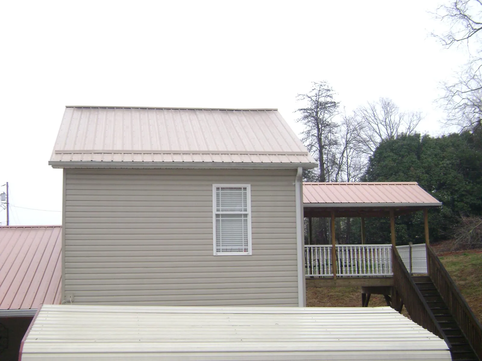 Tan metal roofs on a two story addition and attached porch, from a Roof Replacement job in Derwood