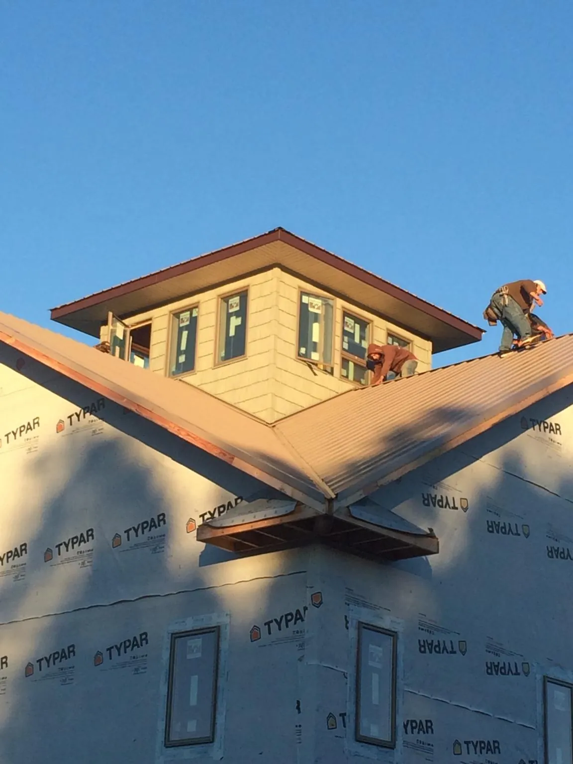 Roofers working around a rooftop cupola on a new metal roof at sunset — Roof Waterproofing in Derwood by Roofing Brothers